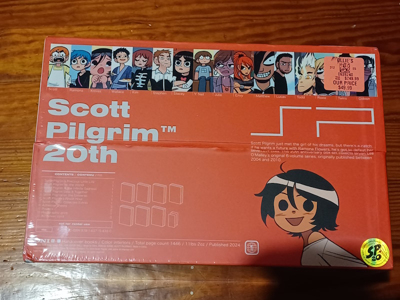 A Scott Pilgrim 20th Anniversary Color Edition box set. The box is red, wrapped in plastic shrink wrap, and has several characters pictured on the top of the box. The character Knives Chau is pictured on the bottom-right. On the top right of the box is an orange price tag. The tag has a QR code and says Ollies, Their Price: $249.99, Our Price: $49.99.